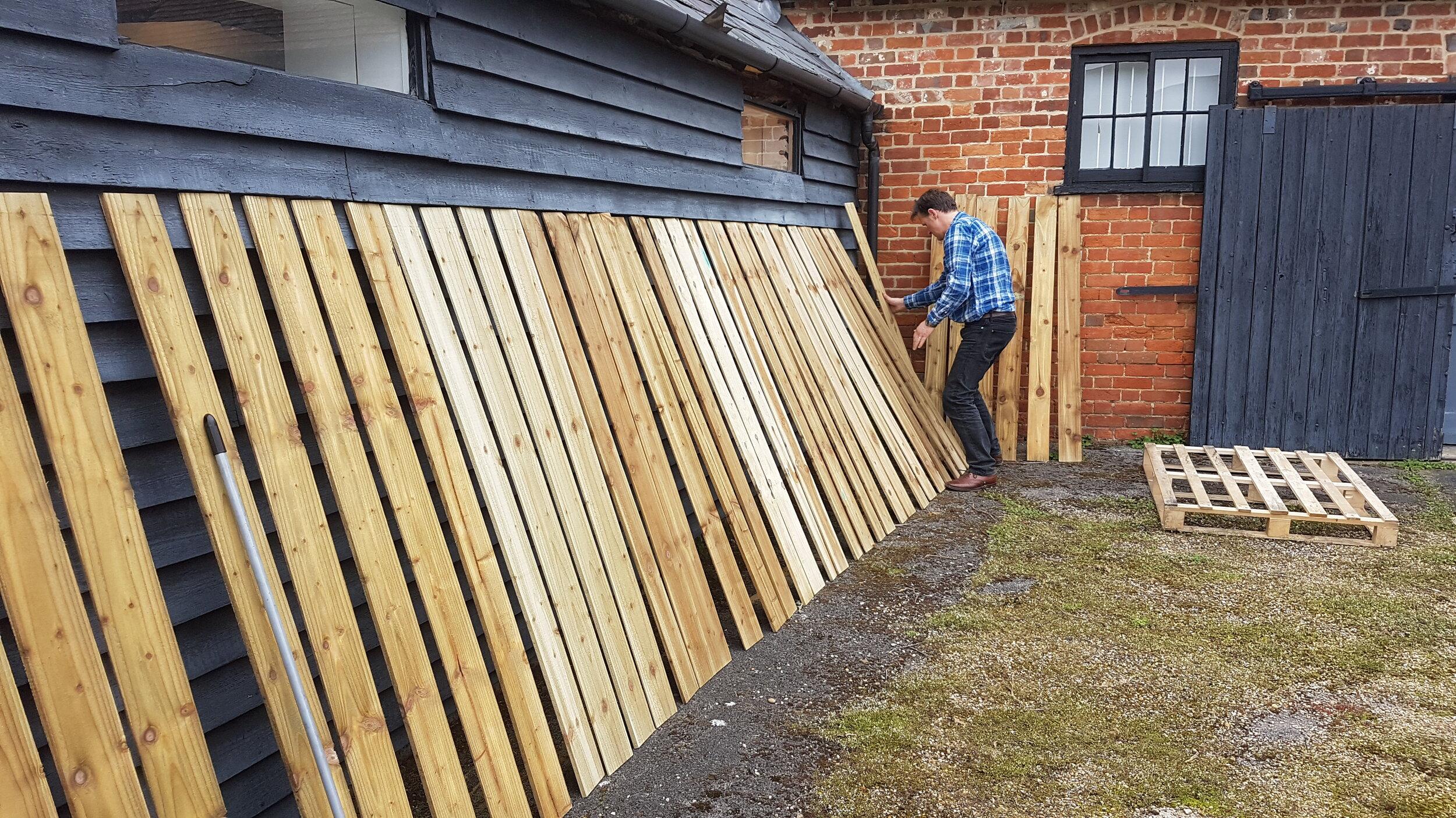 Colin inspecting and cleaning the fence boards outside Timbermark HQ